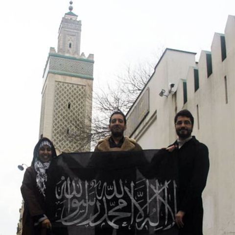 Yassine Ayari en juillet 2013 devant la grande mosquée de Paris, en compagnie d'islamistes tunisiens, montrant l’étendard d'Al-Qaïda récemment repris par Daech.